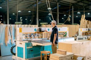 Man in a woodworking factory operating machinery, emphasizing industrial craftsmanship.