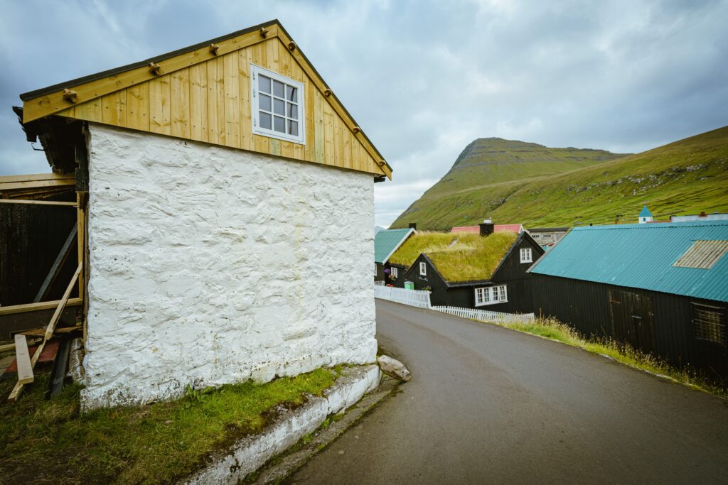 Scenic view of village houses with turf roofs on a hillside under an overcast sky.
